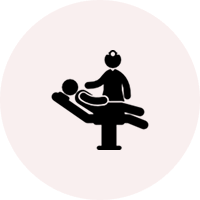 trGroup 23 Icon depicting a dentist with a patient in a reclining chair, symbolizing a dental appointment, on a pink circular background.